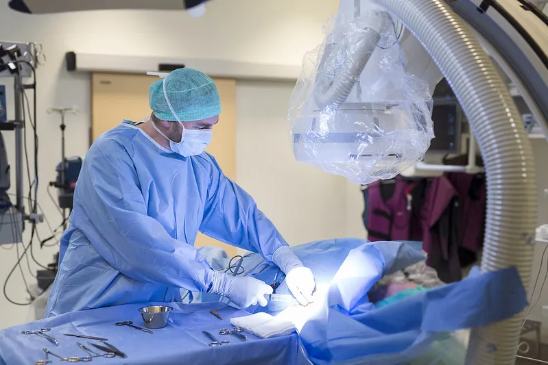 A person in a surgical scrubs and mask in a hospital